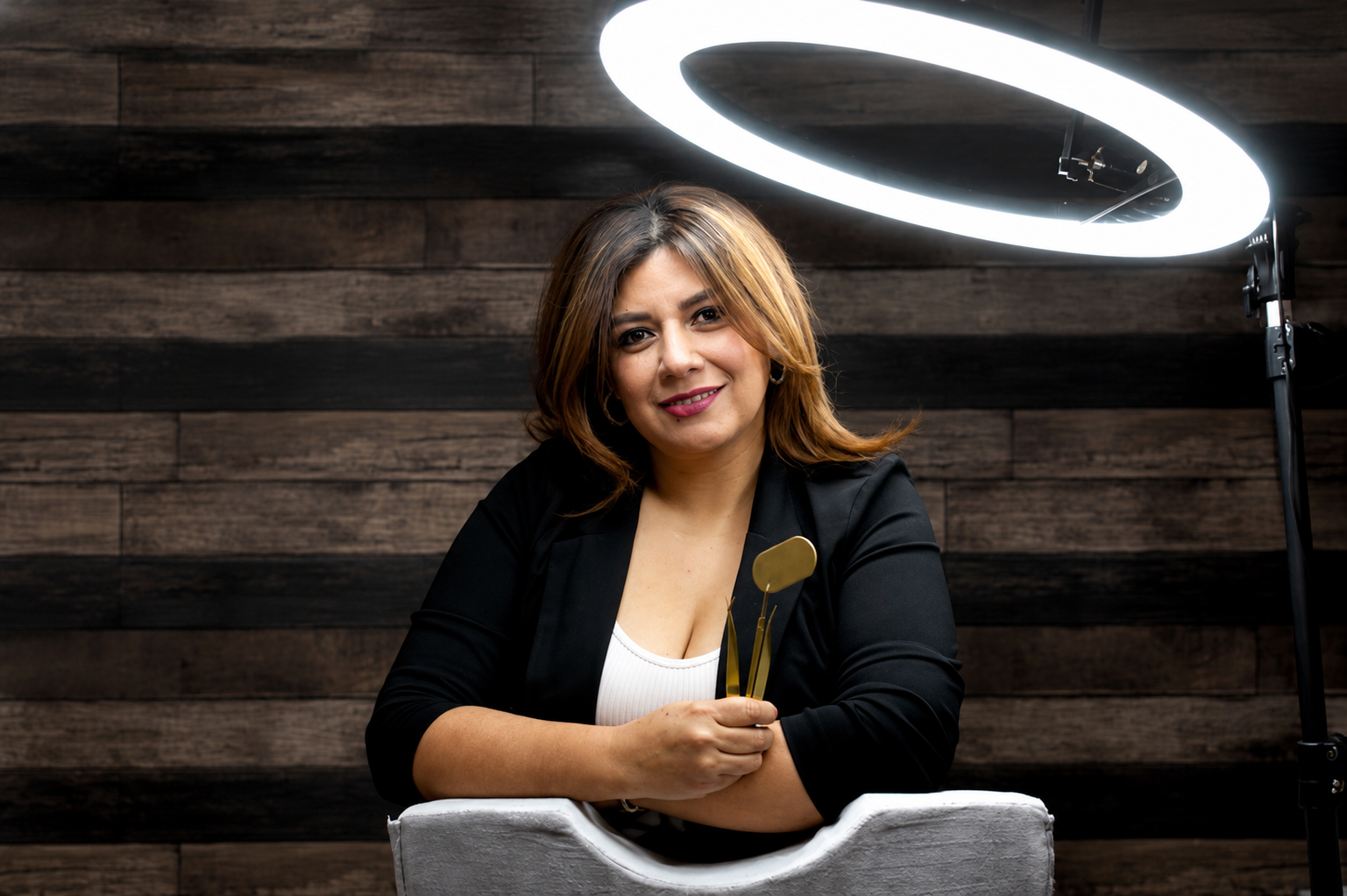 Yuri at her lash studio, holding a lash tool under a ring light